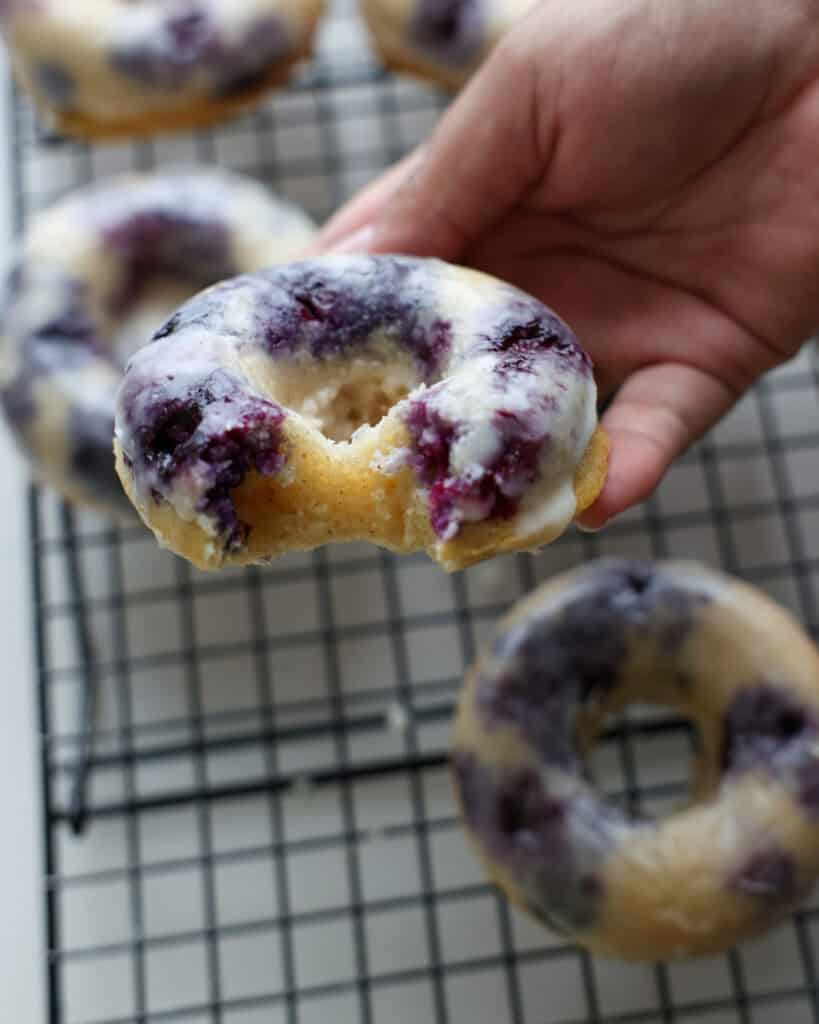 A homemade baked blueberry donut with a bite out of it.