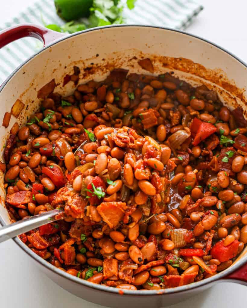 A dark red Dutch oven full of Borracho beans.