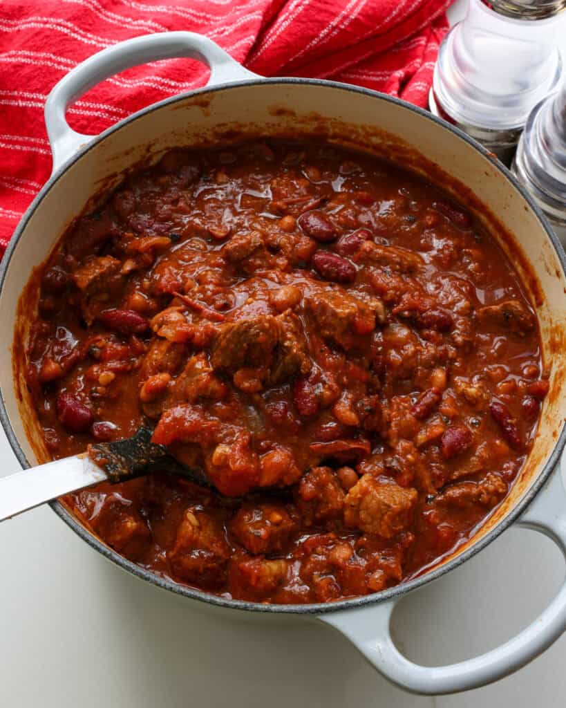 A Dutch oven and a ladle full of beef brisket chili.