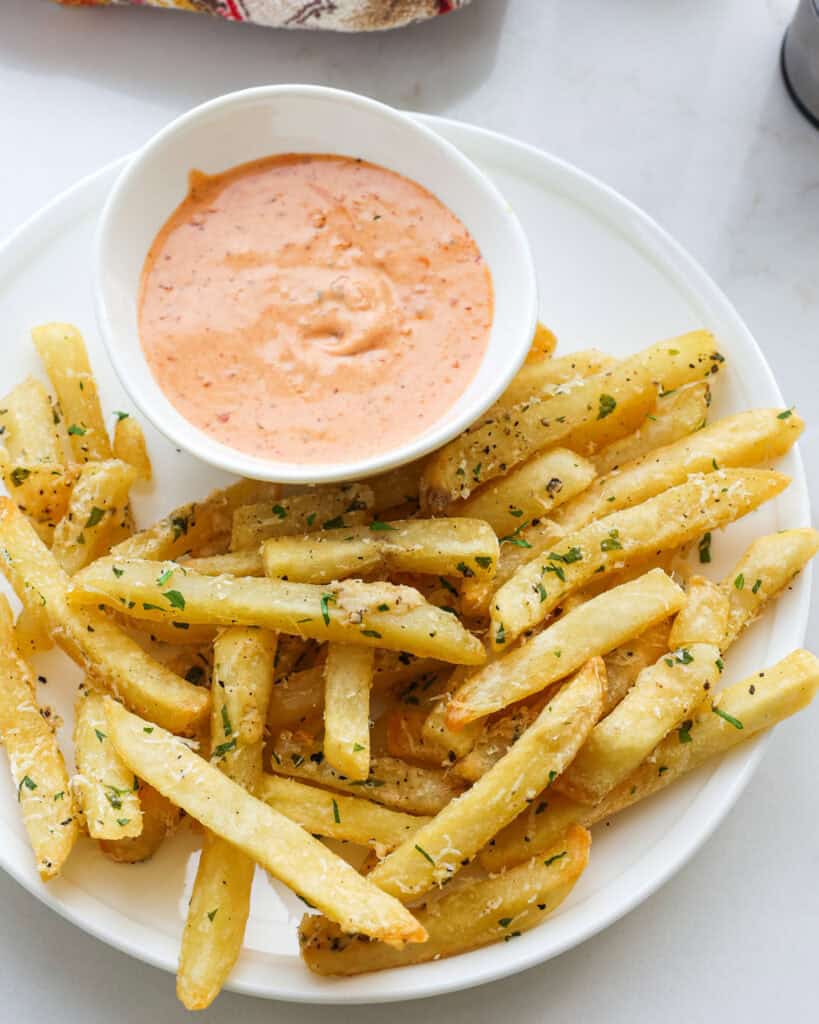 A close up view of truffles fries with Parmesan cheese and parsley. 