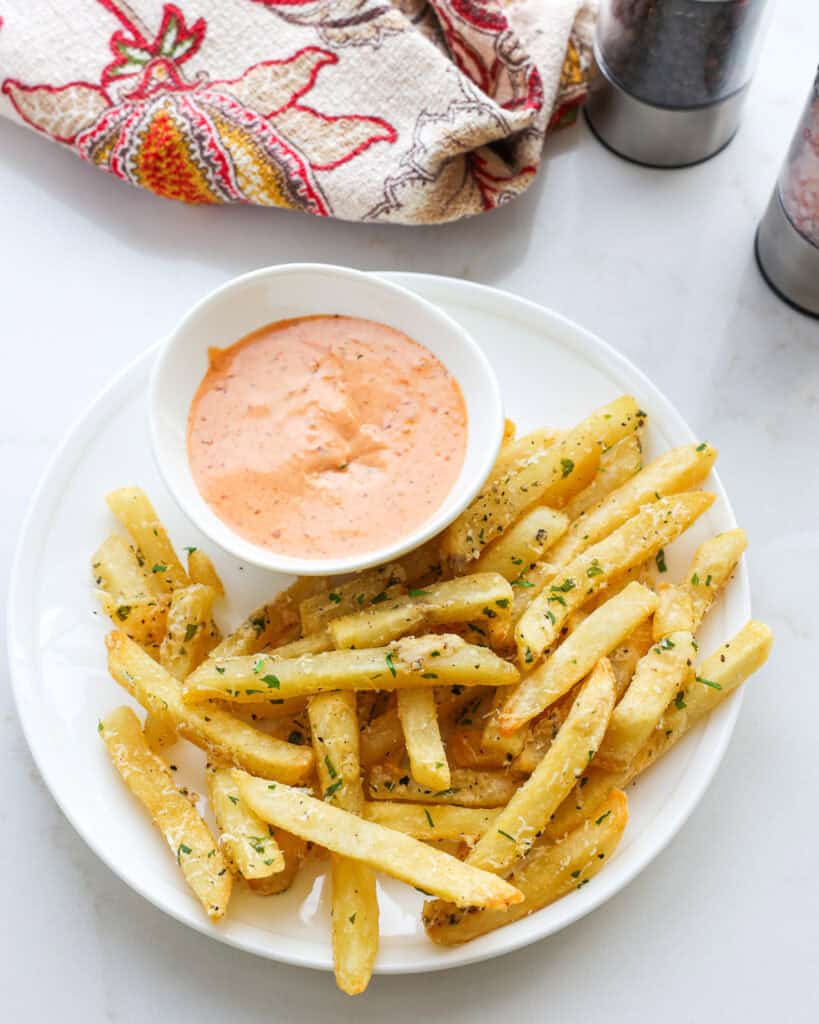 An overhead view of a truffle fries and comeback sauce on a white serving plate.