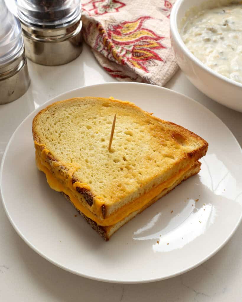 An air fryer grilled cheese sandwich with salt and pepper shaker in the background.