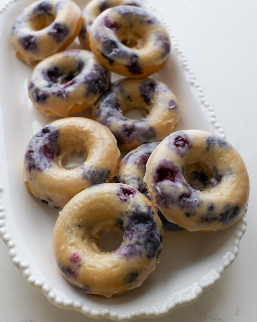 Baked blueberry donuts on a whilte oval platter.