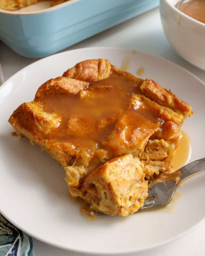 A slice of pumpkin bread pudding topped with salted caramel sauce. 
